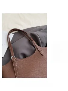Detail of brown litchi leather tote bag with silver adjustable shoulder strap buckle