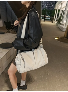 Beige pleated crossbody bag with wide strap worn by model in urban night scene