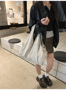 Detail of off-white oversized nylon shoulder bag featuring stitched seams and side pockets