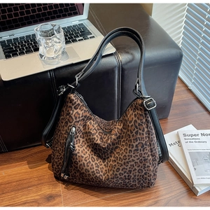 Close-up of leopard print tote bag with black leather handles on wooden floor