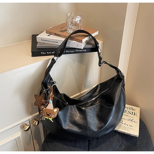 Detailed view of black hobo bag with pebble leather texture and cute plush bear charm