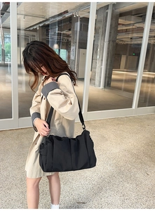 Detailed view of black pleated tote bag showing large capacity and side storage pocket