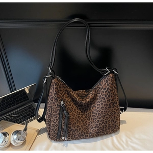 Close-up of leopard print shoulder bag with black leather straps and stylish tassel detail