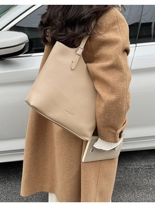 Detailed shot of beige lychee grain leather tote bag worn with a brown wool coat