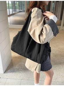 Detailed view of black nylon tote bag showing pleated texture and wide strap for daily use