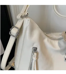 Gros plan du sac en cuir blanc avec bandoulière réglable et boucle en métal argenté