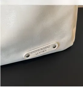 Gros plan sur la texture du cuir blanc avec rivets métalliques et logo sur le sac