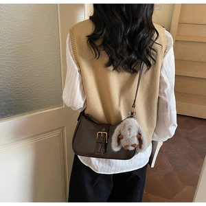 Detail view of a vintage dark brown shoulder bag with a cute plush rabbit charm