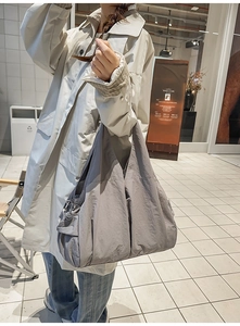 Detail of grey nylon tote bag showing side storage pocket and wrinkled fabric texture