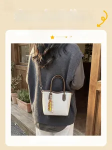 Detail of a beige bucket bag with brown trim and colorful beaded tassel pendant