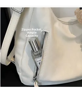 Détail de la poche zippée avant sur le sac en cuir blanc montrant la grande capacité