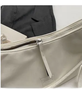 Détail de la fermeture éclair et étiquette classique sur sac hobo en cuir blanc