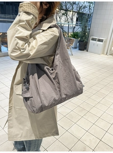 Minimalist nylon tote bag side view showing large capacity on model in beige coat