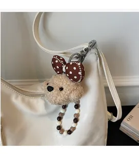 Gros plan d'une breloque de chien en peluche et perles sur un sac à main blanc
