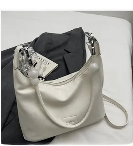 Détail du sac à bandoulière en cuir PU blanc cassé avec perles décoratives et étiquette classique