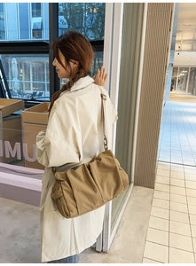 Side view of a khaki canvas crossbody bag with adjustable wide strap and vintage buckles