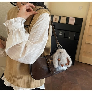 Detail of vintage brown PU leather hobo bag with pin buckle strap and plush rabbit charm