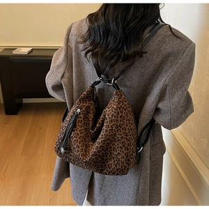 Detail of leopard print crossbody bag featuring silver zippers and adjustable straps