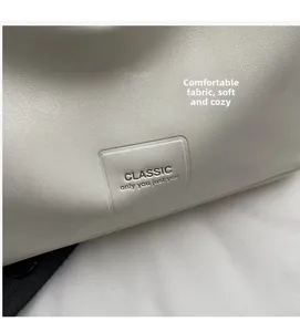 Détail du cuir souple beige avec patch logo gaufré sur le sac à bandoulière chic