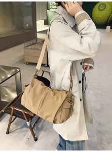 Detail showing khaki pleated shoulder bag texture with wide fabric strap and metal buckle