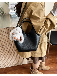 Détail du sac à main en cuir grainé noir avec pendentif lapin en peluche et coupe en V
