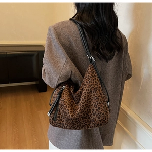 Detailed view of the leopard print tote bag side zipper and black leather strap textures