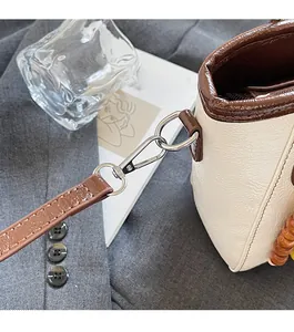 Close-up of cream pebble leather bucket bag with brown accents and silver hardware