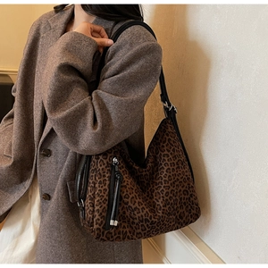 Close-up of leopard print tote bag with black leather strap on female model