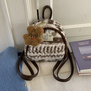 Detail of plush checkered mini backpack featuring brown teddy bear charm and brown straps