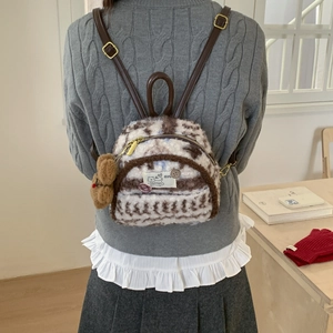 Detail of plush mini backpack with brown lamb wool and cute bear pendant accessory