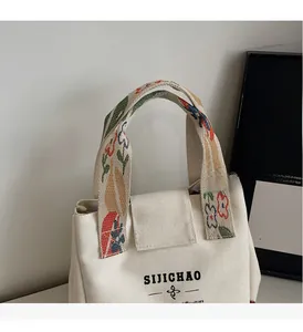 Close-up of white canvas bucket bag featuring vintage floral printed handles and durable texture