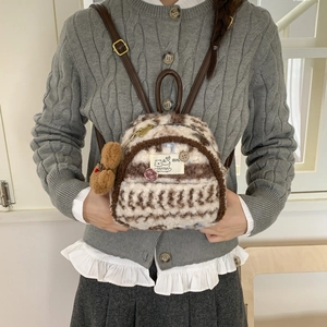 Close-up of plush striped mini backpack with bear charm and leather straps