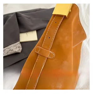 Detail of brown suede tote bag featuring white stitching and gold rectangular buckle
