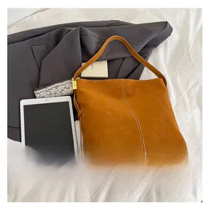 Detailed view of brown tote bag with contrast stitching and tablet for scale