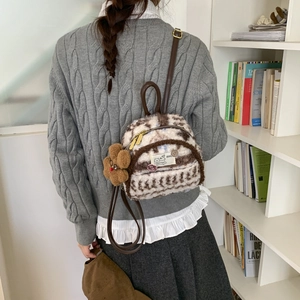 Detailed back view of a mini plush brown checkered backpack on a model in a library
