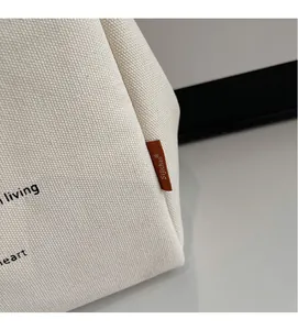 Detailed view of durable beige canvas tote bag with contrast stitching and woven label