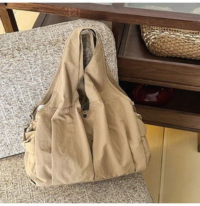 Detail of khaki tote bag showing snap closure and soft nylon texture on tweed chair