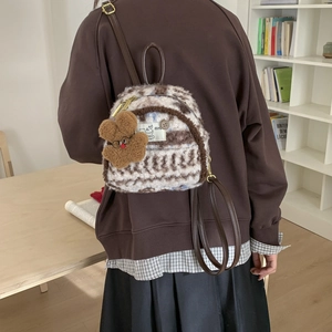 Close-up of plush vintage plaid backpack with a cute rabbit pendant and logo detail