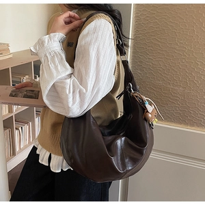 Deep brown PU leather crescent hobo bag with cute bear charm shown in casual street style