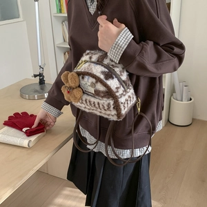 Close-up of mini faux fur cow print backpack with cute bear pendant and gold zippers