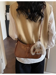 Brown glossy crescent shoulder bag with gold buckle and rabbit plush pendant detail