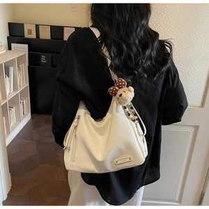 Détail du sac hobo blanc cassé avec fermeture éclair argentée et breloque ourson