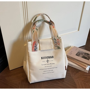 Detail of canvas bucket bag with floral embroidery on colorful woven handles