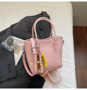Detail of pink faux leather bucket bag with beaded tassel and fashion logo