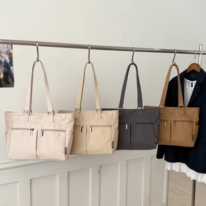 Detail view of multi-pocket canvas tote bags in cream, khaki, grey and tan colors