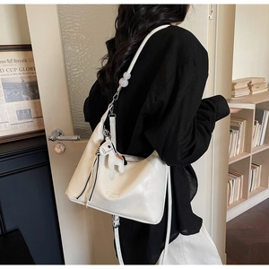 Détail du sac hobo en cuir blanc avec bandoulière perlée et accessoire breloque zèbre