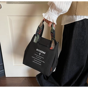 Close-up of black canvas bucket bag featuring floral patterned handles and white text print