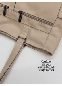 Λεπτομερής κοντινή λήψη μεταλλικού φερμουάρ και ενισχυμένων ραφών σε μπεζ υφασμάτινη τσάντα