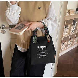 Detail of a black canvas tote with floral embroidered handle and inspirational text print