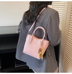 Pink crossbody bucket bag with wood bead tassel and textured faux leather finish